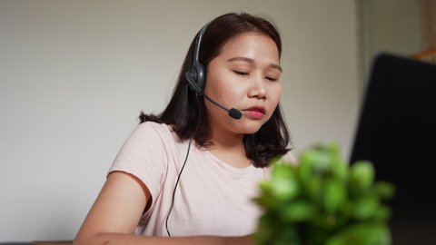 slow motion scene on young call center employee woman wear headset to talking with colleagues and partner at desktop in living room for customer care and work from home concept