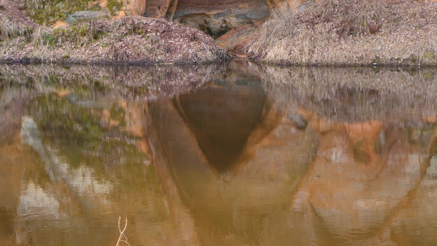 A nature-created angelic cave on the river bank. Protected rock by the river. Sandy rocks by the river. Sand rock a few meters high. Mazsalaca.