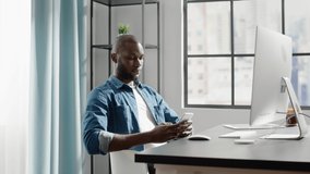 Happy black freelancer puts aside smartphone and starts to type on contemporary white computer keyboard at desk at home slow motion - Powered by Shutterstock - Get 15% off with code: PIKWIZARD15