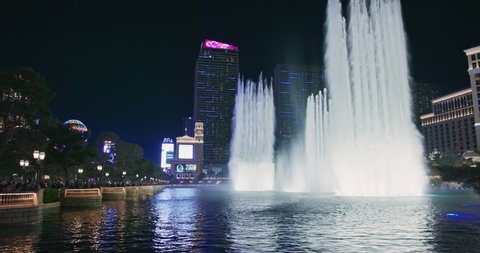 Las Vegas, Nevada USA, March 2021. Fountains at Bellagio Casino with Cosmopolitan hotel building on background. World famous attractions and night shows on Las Vegas Strip. Night footage 4K