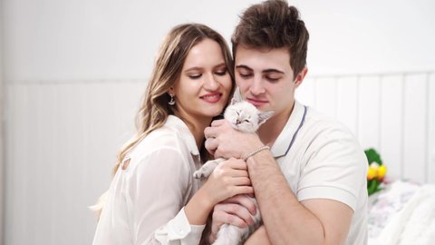 A beautiful couple of young lovers holding a small white kitten. cat breed Nevsky masquerade. pet in a young family.