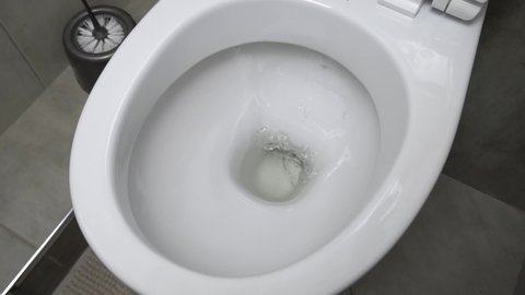 Flush toilet. Water flushes the toilet. The flow of water is clearly visible. Flashing water in a ceramic toilet. slow motion