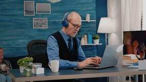 Focused old entrepreneur with headphones listening music while checking graphics writing on laptop working from home. Retired man using modern technology reading typing, searching on computer - Powered by Shutterstock - Get 15% off with code: PIKWIZARD15