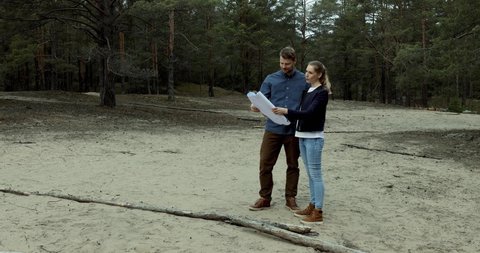young couple choosing a plot of land for forest lodge construction