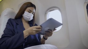 Asian businesswoman wearing face mask and Use tablet to work while traveling on airplane. Wear mask Prevent of COVID-19 Or bacterial viruses that dangerous to people. Concept Health care insurance