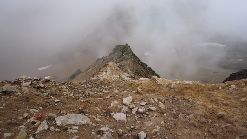 Mountain pass with crumbling stones in the fog. Cloudy. Caucasus, Russia.