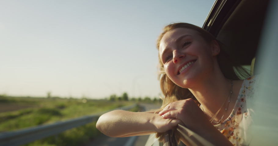 Authentic Shot of an Young Happy Carefree Blonde Hair Woman is Enjoying and Having Fun to Look out the Car Window During a Trip with Friends in a Sunny Day. | Shutterstock HD Video #1070622637