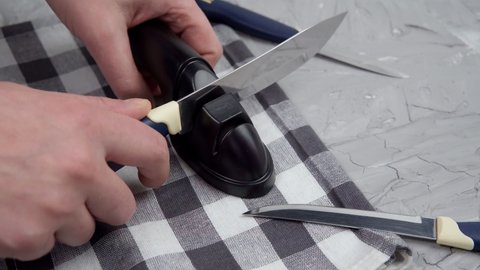 man is sharpening kitchen knives. sharpening a knife with a home sharpener. selective focus