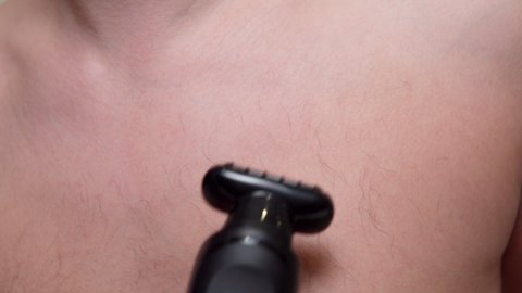 shaves her chest hair with an electric trimmer. selective focus