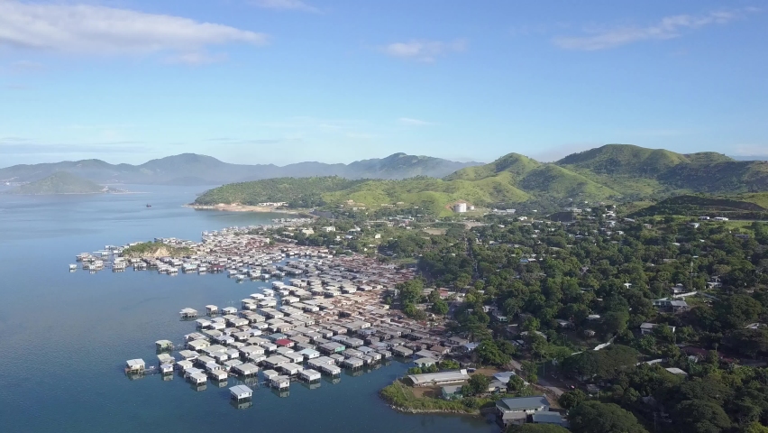 Port Moresby Fishing Village flyover, three quarter angle mountains in background beautiful water