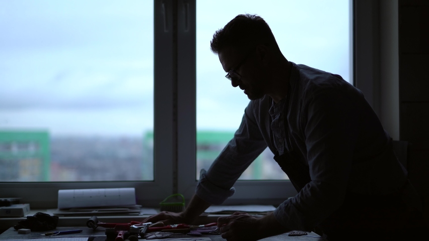 Silhouette of a worker artist or professional industrial designer in a studio. Working place of a professional doing manufacture. 4k footage