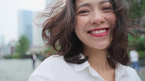 slow motion of lovely asian girl looking at camera smile in the urban city with camera moving around 360 degree