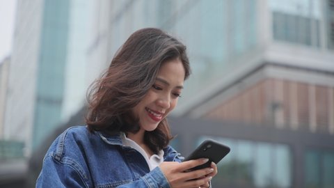 4k slow motion close up of one young asian woman holding mobile phone typing reading news online in the urban city place at Chengdu China