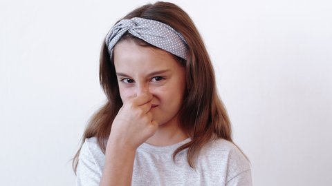 Disgusted child. Refusal disagreement. Spoiled dissatisfied picky naughty skeptic little girl rejecting offer holding nose to avoid bad smell showing no sign isolated on light neutral background.
