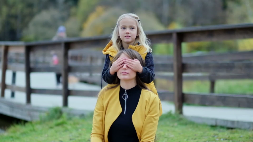 Beautiful young woman and her charming little daughter have fun in the park. Daughter hugging mother on nature. Slow motion video. stock footage
