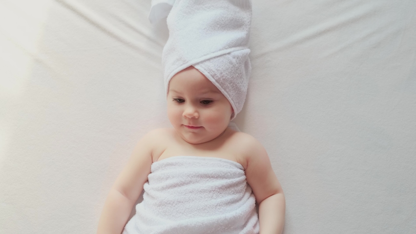 Happy child lies on the bed wrapped in a towel after bathing. Body Care | Shutterstock HD Video #1070634082