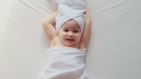 Happy child lies on the bed wrapped in a towel after bathing. Body Care