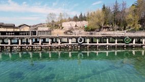 A drone video of a long wooden pier on Lake Ohrid, close to the city of Ohrid in North Macedonia on a sunny afternoon in Spring.
