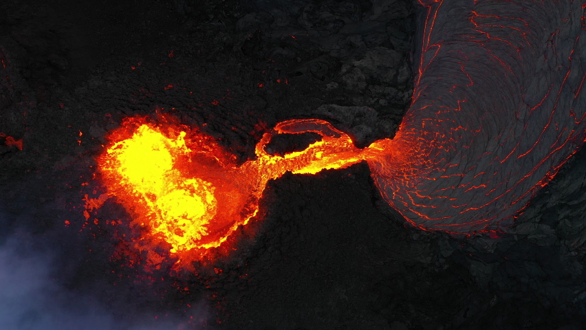 Aerial view looking straight into an erupting volcano and lava flowing from it, Shot in Iceland in 2021