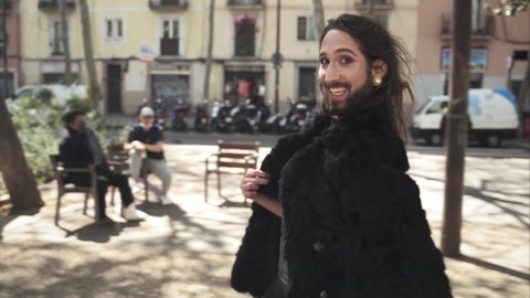 Cheerful transsexual Drag Queen man with beard and elegant dress walking in the city. Respect, sexual equality, diversity and pride for lgbt people
