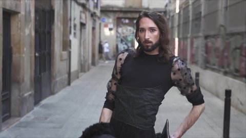 Drag Queen Transgender with beard, dark dress skirt and high heeled boots walking in the narrow streets of European city (Barcelona). Respect, sexual equality, diversity and pride for lgbt people