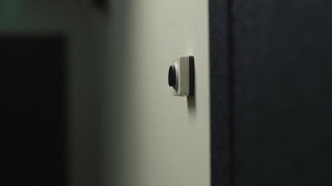 Close-up hand of unrecognizable man pushing doorbell button in entryway of apartment building. Delivery man ringing on doorbell to meet customer and hand over online order. Shooting in slow motion.