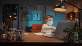 Students return to school after COVID 19 Coronavirus lockdown, kid wearing a mask doing homework on video conference call, asks questions, social distancing in the classroom. Remote home video lesson
