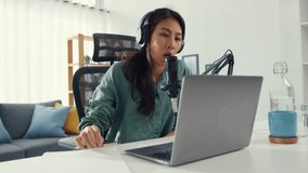 Happy asia girl record a podcast on her laptop computer with headphones and microphone talk with audience at her room. Female podcaster make audio podcast from her home studio, Stay at house concept.