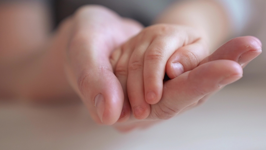 mom holds the hand of a newborn. close-up baby hand. hospital caring happy family medicine concept. baby newborn holding mom hand close-up. mom takes care of the baby in indoor the hospital Royalty-Free Stock Footage #1070647408