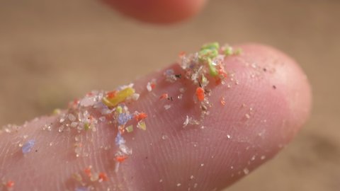 pieces of microplastic on the finger. primary and secondary microplastics. small plastic pellets in human hands. soil contamination, marine plastic pollution, environment, ecology, earth