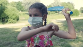 Beautiful little girl plays badminton in a medical mask. Virus protection. 4K video.