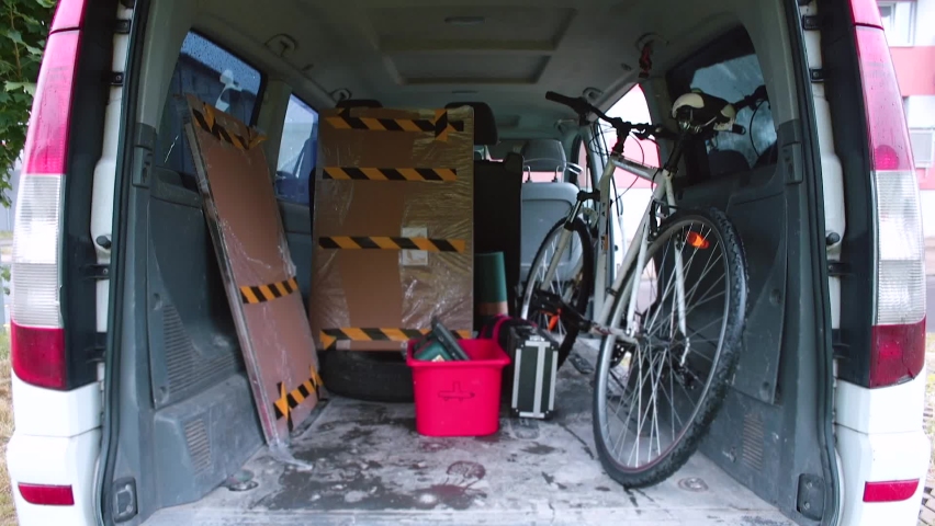 Man talking on phone in trunk car. He transmits verbal messages using telephony. Transportation by carrying loader. Waiting for the client, delivery of things. Using phone. 