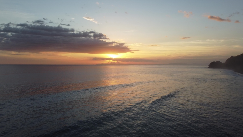 4k top view of the fantastic Pacific Ocean sunset. Beautiful aerial view of the sunset over waves. Golden cloudy sky with amazing seacoast scene.