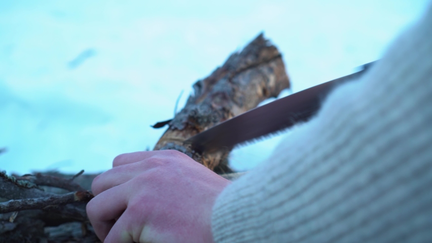 Man sawing up firewood while hiking in the mountains 4k