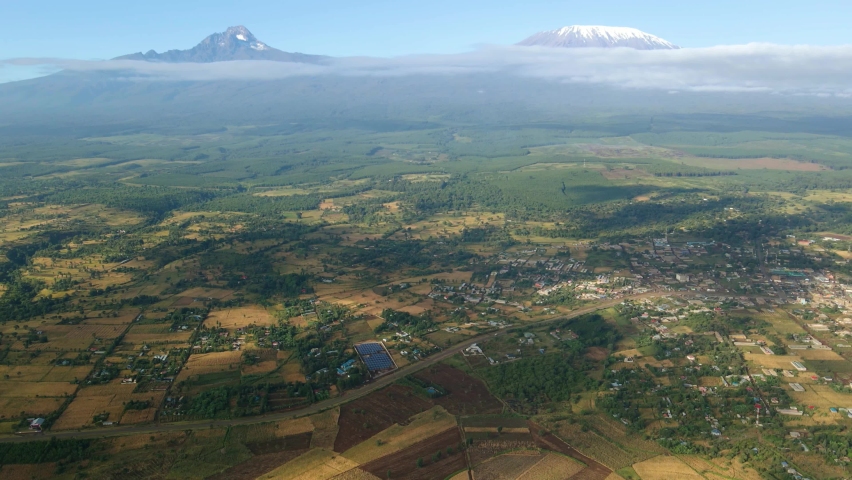 Aerial view cloud shadows moving over fields on the countryside of Kenya, Kilimanjaro mountain background - tracking, drone shot