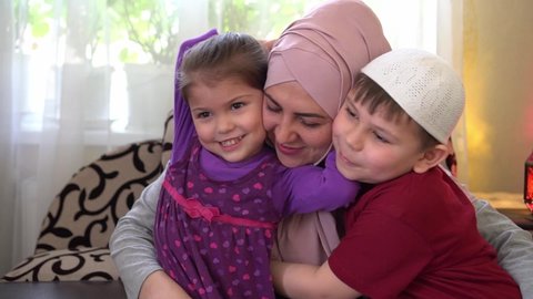 Ramadan mubarak. Muslim family at home together. Happy woman celebrates Eid holiday with a little daughter and son. Children hug their mother