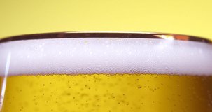 Close up of foamy beer being poured into glass with water drops .ultra high definition 