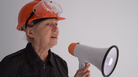 Expressive woman in safety helmet shouting into megaphone. Portrait of adult emotional construction worker. News announcement and advertisement - Powered by Shutterstock - Get 15% off with code: PIKWIZARD15