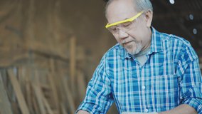 Asian senior male carpenter equals a wooden bar in the workshop. Carpentry, craftsmanship, Handicrafts. - Powered by Shutterstock - Get 15% off with code: PIKWIZARD15