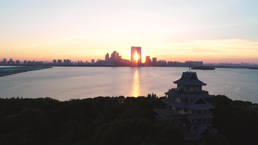 Aerial cityscape of a pagoda, boats and skyline in the sunset on Jinji lake, Suzhou, China. Camera moves right