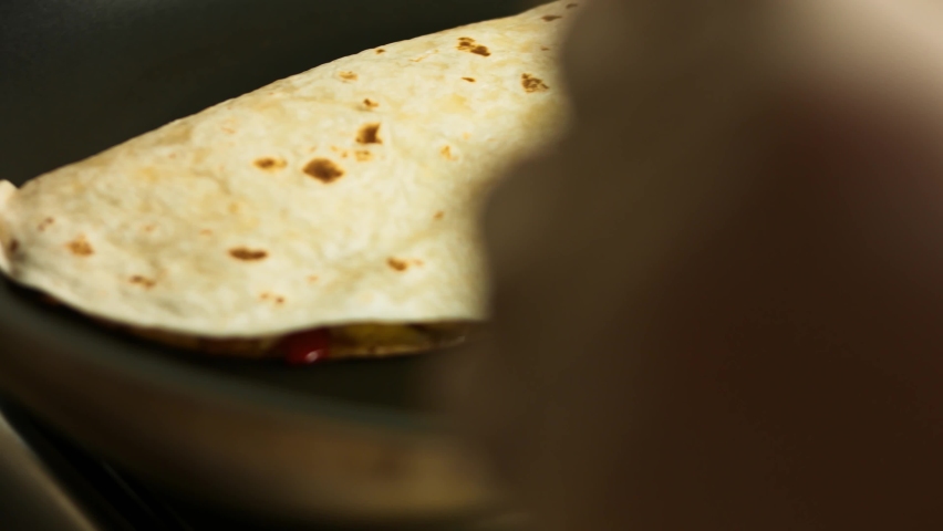 Frying a freshly wraped chicken quesadilla on a frying pan. Turning over the quesadilla. Process of making mexican quesadillas Royalty-Free Stock Footage #1070672929