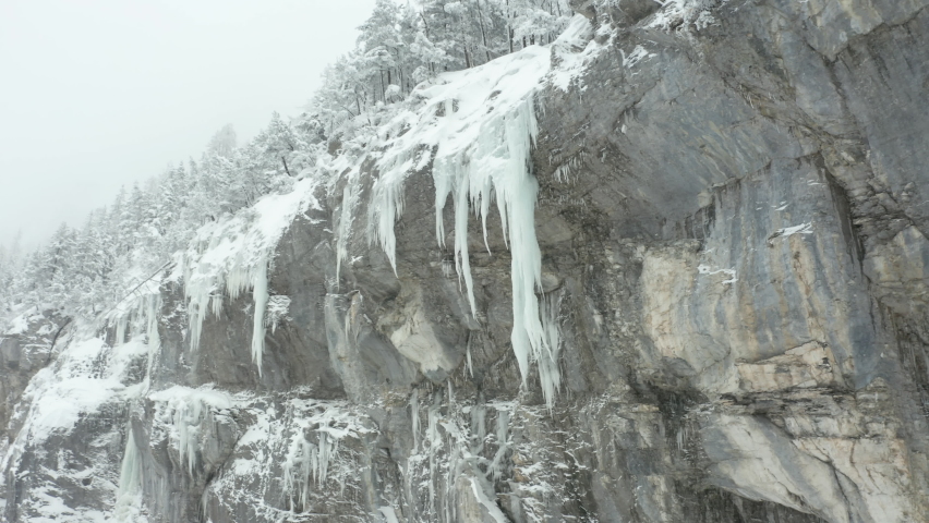 Low angle dolly of large icicles hanging of mountain ridge