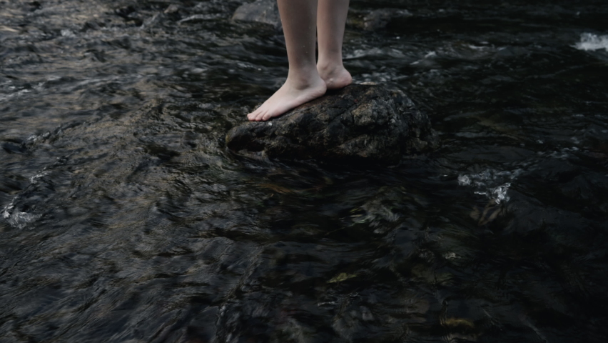 Woman standing on the big stone watching the beautiful view point on the stream in forest.