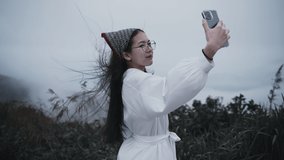 Asian woman using smartphone recording the video camera of wonderful mountain in Chang Suek hill Thongphaphum Kanchanaburi, Thailand.