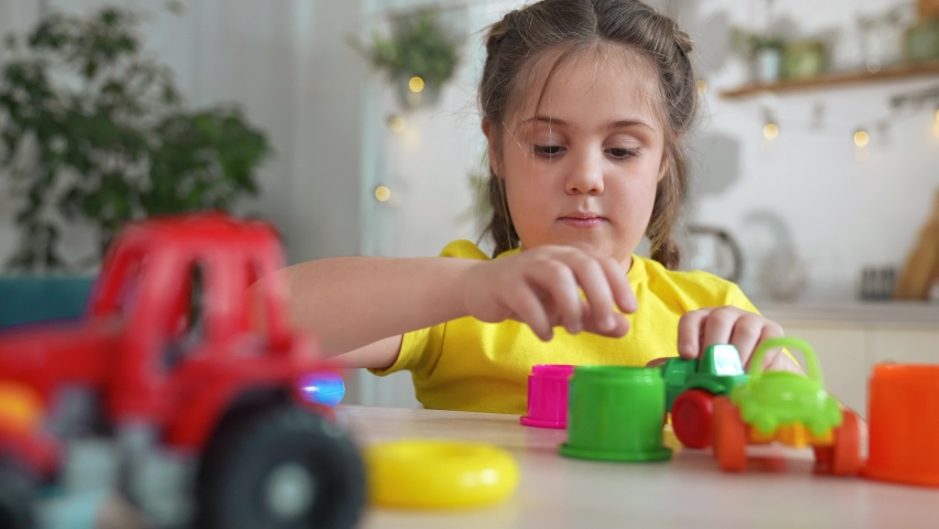 little girl play a with toy car. baby kid plays with toys and rolls the car in the parking lot. play with toy car on the table. child plays with toys at home. kid dream happy childhood indoor concept