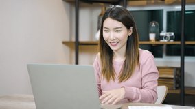 Asian woman using laptop making video conference or online support remote working from home