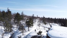 Aerial video from the drone. A happy and handsome guy with a wonderful smile admires the beauty of nature in the Stone Town National Park in the Ural Mountains. Perm Territory, Russia.