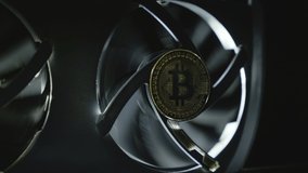 Cooling fans are spinning on the video card, Bitcoin coins are shine in light as a symbol of cryptocurrency mining using computer video cards. Macro. Closeup. In work video adapter (graphics adapter)