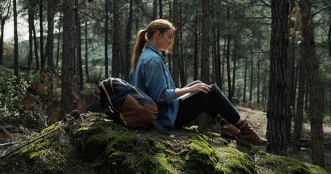 Young woman with backpack working on the laptop in nature