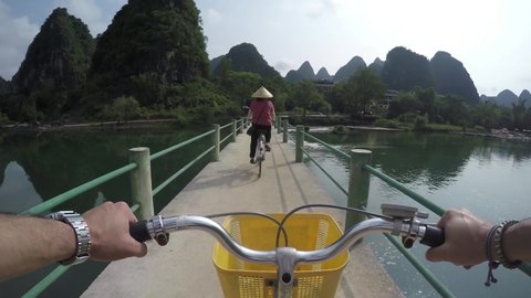 First person view bicycling over Yulong River bridge in Yangshuo County China very popular chinese tourist destination for both foreign as domestic tourists area is known for the karst peaks mountains